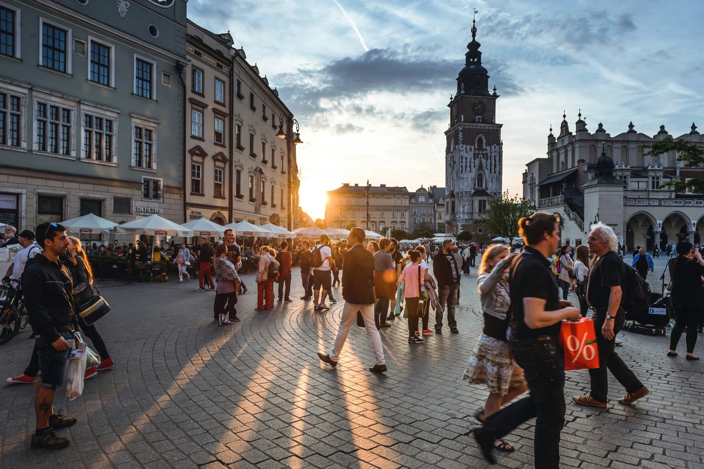 Crowds of travelers filling a European city square at sunset